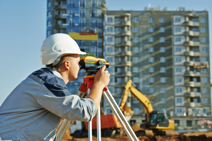 Arbeitnehmer mit Vermessungsinstrument auf einer Baustelle